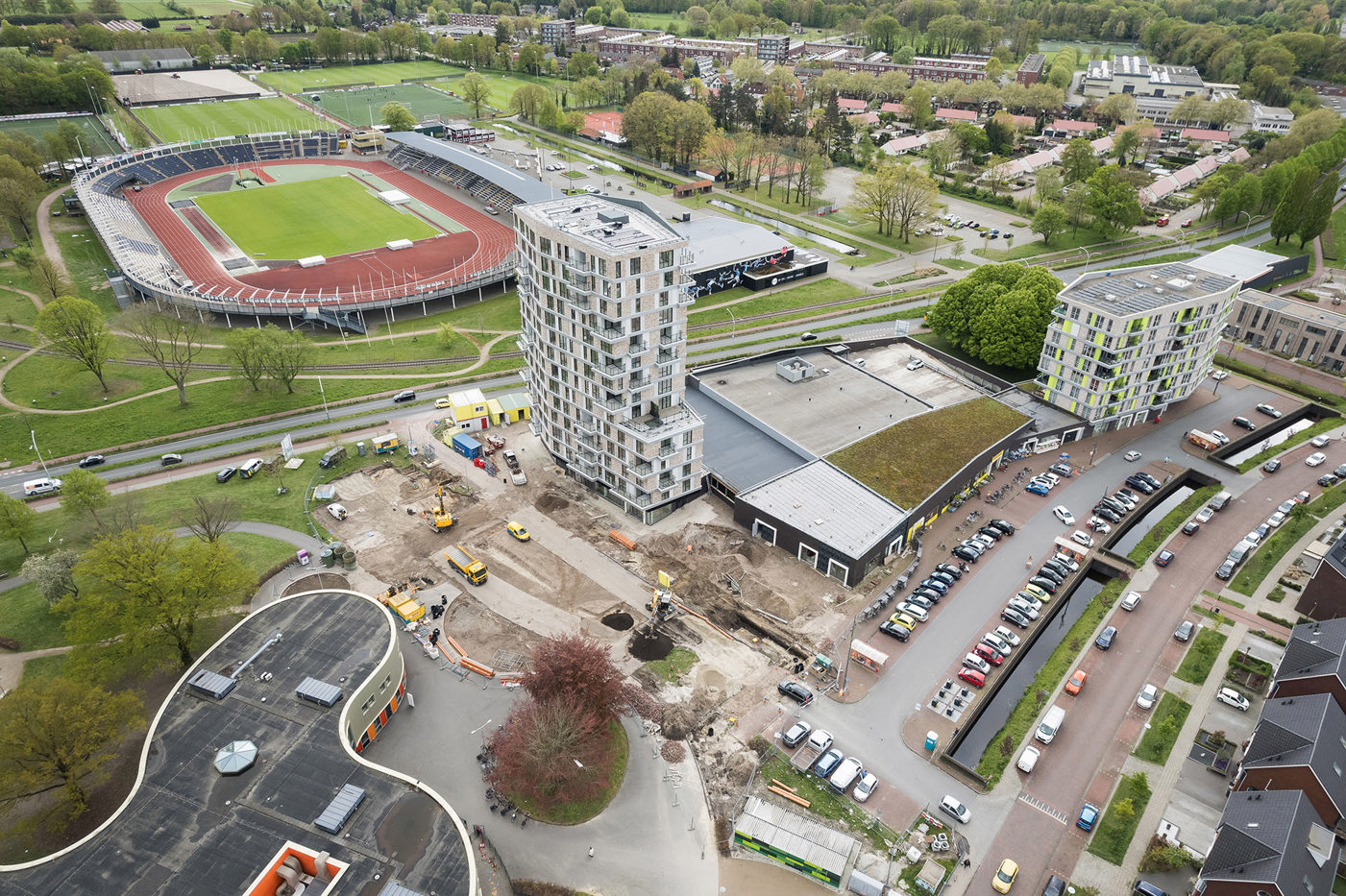 De Apollo toren met erbij een parkeerplaats met auto's, stadion achter de toren, hele woonwijk er nog achter en naast