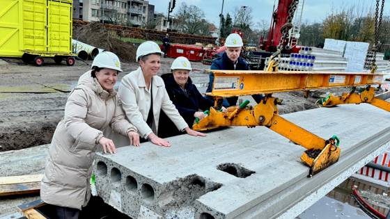Gedeputeerde Liesbeth Grijsen, wethouder Hannie Rohaan van de gemeente Hof van Twente en bestuurder Lianne ter Stal van Wonen Delden leggen samen de eerste vloerplaat 