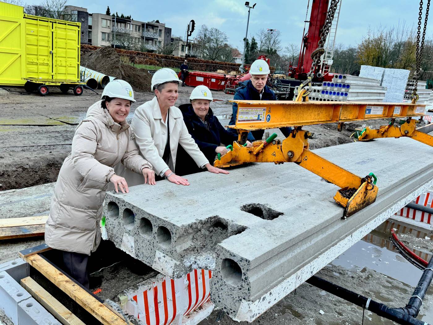 Gedeputeerde Liesbeth Grijsen, wethouder Hannie Rohaan van de gemeente Hof van Twente en bestuurder Lianne ter Stal van Wonen Delden leggen samen de eerste vloerplaat 