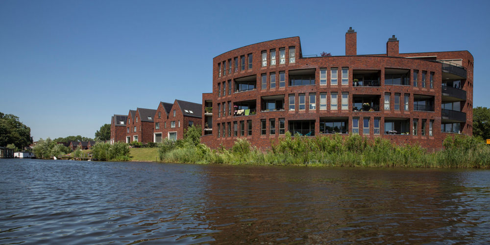 Twee onder een kap huizen en appartementencomplex voor een brede sloot